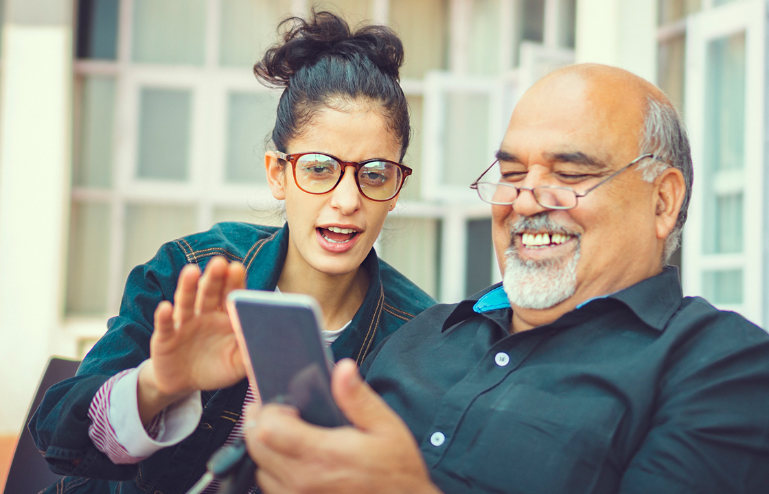 young woman showing older gentlemen something on a mobile phone